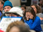 A woman wearing blue to support the Portland Association of Teachers, drops her face in her hands as she listens to statements from students, teachers and parents during a Portland Public Schools Board of Education meeting at the PPS district office in Portland, Ore., on Nov. 7, 2023.