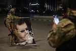 A Syrian opposition fighter takes a picture of a comrade stepping on a portrait of Syrian President Bashar Assad in Aleppo, early Saturday.