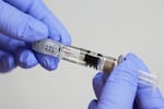 FILE - A certified medical assistant holds a syringe for a flu vaccine at a clinic in Seattle, on Sept. 10, 2025.