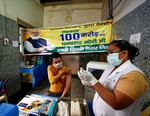 A health worker inoculates a man next to a banner thanking Prime Minister Narendra Modi for 1 billion doses of COVID-19 vaccine at a government hospital in New Delhi, India.