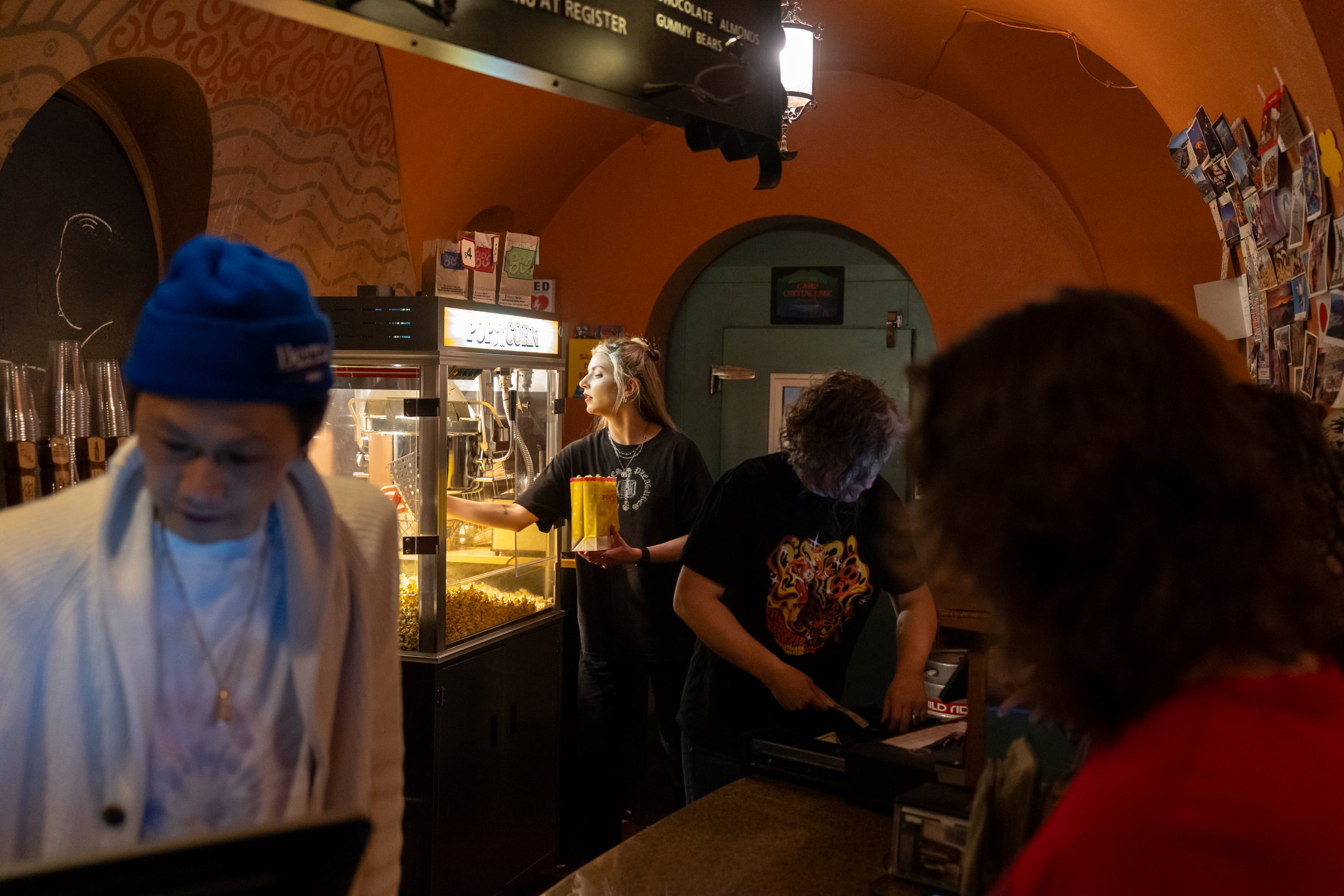 Chloe Skaar, theatre floor manager, serves popcorn for movie-goers as volunteers John Vuong, left, and Jodi Morris take orders at the century-old Hollywood Theatre in Portland, Ore., on Feb. 4, 2026.
