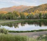 A body of water in front of a low range of hills, with higher mountains visible in the background.