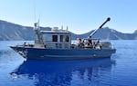 Researchers aboard the R/V Neuston testing water clarity on Crater Lake.