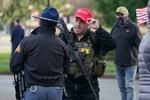 An armed supporter of President Donald Trump speaks casually with a Washington State Patrol trooper during a rally, Sunday, Jan. 10, 2021, at the Capitol in Olympia, Wash. Protesters from several causes rallied Sunday at the Capitol, the day before the 2021 legislative session was scheduled to begin.