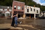 Resident Anne Schneider, right, hugs her friend Eddy Sampson as they survey damage caused by Hurricane Helene in Marshall, N.C. in 2024.