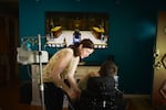 Shasta Kearns Moore administers fluids through a feeding tube to her son Malachi, who requires daily medical care after being born prematurely at 29 weeks. Malachi has had outside care workers, but says he prefers his mother to care for him because she knows him best.