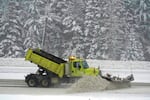 A snowplow pushes snow off a road.
