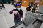 Poll worker Kathy Richardson uses a spray bottle to sanitize a voting booth out of concern for the coronavirus in a polling station at Marshfield High School, Tuesday, Nov. 3, 2020, in Marshfield, Mass.
