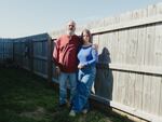 Shante Benfatto, a military veteran, and husband Mark Benfatto outside their home in Clarksville, Tenn. Mark has his arm around Shante as they stand next to their wooden fence. He has a gray beard and she has shoulder-length hair that is blond and brown.