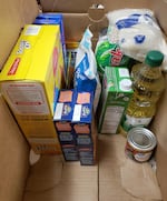 Meat and dairy products are added to a food box to support a family of four, at Agape House in Hermiston, Ore., Nov. 12, 2021. The charity is facing difficulties in acquiring some crucial things such as Campbell’s Soup, due to supply chain delays.