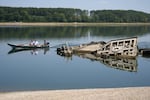 People watch the wreckage of a WWII German warship, emerged due to the drought, in front of Djerdap II, a large dam on the Danube River, between Romania and Serbia, near Prahovo, Serbia, Tuesday, Aug. 4, 2026.