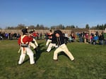 A 2018 reenactment at Fort Vancouver National Historic Site of a mid-19th century “Brigade” when the company employees returned to the fort after months of trapping furs in outlying areas. Both Navy sailors and the Marines trained in the use of cutlasses (a type of saber). In the photo, the Royal Marines are in red uniforms, Royal Navy in blue. At front right, Instructor-at-Arms Jeff Richardson of Academia Duellatoria. The reenactors are conducting a partner drill.