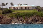 Jeffery Epstein's white mansion on the island of Little Saint James sits above a cliff that meets the blue Caribbean Sea, on July 9, 2019. A few palm trees are on the left side of the frame.