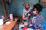 Mariam Hassan sits in front of a mirror getting her hair blow-dried by Saly Amutwayi.