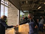 Local Ocean Seafoods owner Laura Anderson, right, hands a seafood meal kit to a customer who signed up for the company's new "Dock Box" offering.