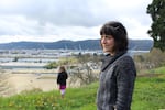 North Portland resident Stacey Schroeder stands on the bluff along WIllamette Boulevard overlooking Swan Island and the Daimler Trucks North America plant, as her daughter picks dandelions in the distance. Schroeder and other neighbors blame Daimler for paint odors in their neighborhood, and they blame the Oregon Department of Environmental Quality for failing to fix it.