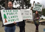 Opponents of a plan to sell the Elliott State Forest hold signs outside an Oregon State Land Board meeting.