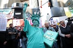 A person dressed in a Statue of Liberty costume participates in a "No Kings" national day of protest in New York on Saturday. Millions of people are expected to attend similar protests across the country, organizers say.