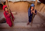 FILE: Zareena, left, and Shakeela, internally displaced Afghan girls play outside a shanty at a refugee camp in the outskirts of Kabul, Afghanistan, Monday, July 25, 2011.
