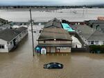 This aerial photograph shows a car and market shop in floodwaters in Pajaro, Calif., on Saturday. More rain and snow is expected in the state this week.
