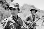 Two guerrillas from the Fuerzas Populares de Liberación, FPL, watch a low-flying Salvadoran military observation plane near the Guazapa volcano on the road to Suchitoto, El Salvador, October 21, 1983. (Photo by Robert Nickelsberg/Getty Images)