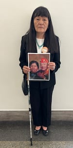 Maggie Billiman holds a picture of her late parents, Mary Louis and Howard Billiman. She believes her father died of cancer related to his exposure to nuclear fallout.