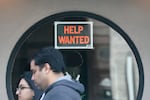 FILE - Pedestrians walk past a help wanted sign posted on the door of a restaurant in San Francisco, Tuesday, April 18, 2023.