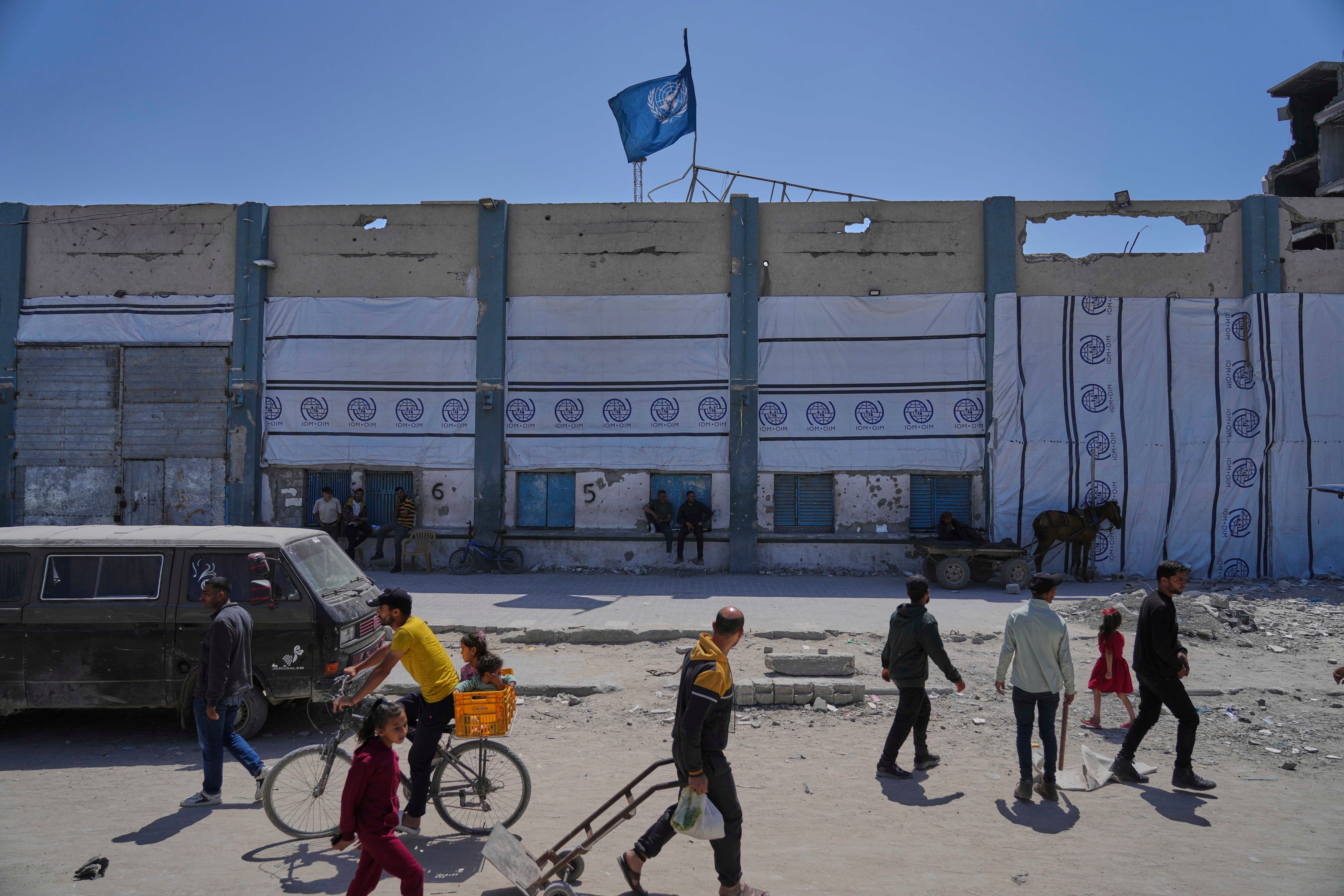 Palestinians walk next to the closed humanitarian aid distribution center of UNRWA, the U.N. agency helping Palestinian refugees in Jabaliya, Gaza Strip on Tuesday, April 29, 2025.