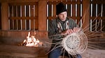 Jordan Mercier weaves gathered hazel sticks into a basket at the Chachalu Museum and Cultural Center in Grand Ronde in June 2022.