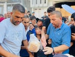 Volunteers Naeem Salem, Nabeel Nassar, and Motaz Ziyada, (from left to right), stand at the food kitchen and help pass out bread to people in north Gaza.