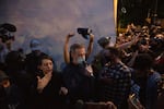 A demonstrator holds a police hat above Mayor Ted Wheeler's head at a protest against police brutality and systemic racism in Portland, Ore., July 22, 2020. Wheeler has faced criticism for the Portland Police Bureau's use of force against demonstrators long before federal officers' arrival.