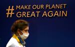 A woman walks by a sign that says "# Make Our Planet Great Again" inside the venue of the COP26 U.N. Climate Summit in Glasgow, Scotland, Tuesday, Nov. 2, 2021.