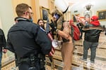 In this Jan. 6, 2021, file photo supporters of President Donald Trump are confronted by U.S. Capitol Police officers outside the Senate Chamber inside the Capitol in Washington. An Arizona man seen in photos and video of the mob wearing a fur hat with horns was also charged. Jacob Anthony Chansley, who also goes by the name Jake Angeli, was taken into custody Jan. 9.