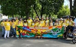 Supporters of Project Sunrise wear bright yellow shirts in this year's Boatnik Parade in Grants Pass. The project, spearheaded by The Oregon Remembrance Project, seeks to create communities as "sunrise towns," where all are welcome and feel safe instead of "sundown towns" that excluded Blacks and other people of color.