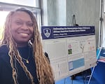 Kimiko Krieger, an assistant professor of biochemistry and molecular biology at the Bloomberg School for Public Health at Johns Hopkins University, stands before a poster describing her research that lost federal funding.
