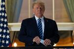 In this Monday, Oct. 5, 2020, file photo, President Donald Trump holds his mask after removing it from his face as he stands on the Blue Room Balcony upon returning to the White House in Washington from the Walter Reed National Military Medical Center in Bethesda, Md. He announced he tested positive for the coronavirus on Oct. 2.