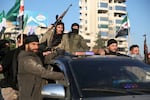 Antigovernment fighters brandish their guns as they ride a vehicle in Syria's northern city of Aleppo on Nov. 30.