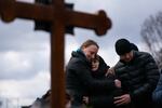 Ukrainian journalist-turned-soldier Viktor Dudar's mother (center) grieves at his grave as he's laid to rest in Lviv last March.