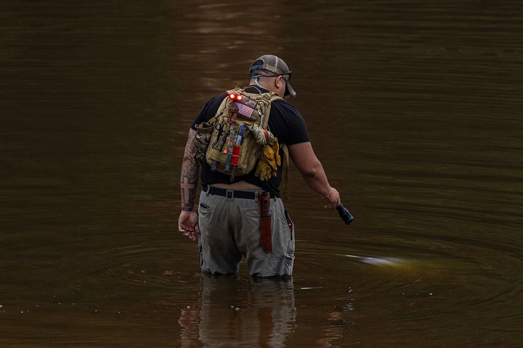 A search and recovery worker shines his flashlight through murky waters on July 6 in Hunt, Texas, two days after deadly flash floods tore through the area.