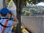 Climate activist Melanie Plaut, who's part of the group 350PDX, looks through binoculars at a row of tanker cars to determine what they're carrying.