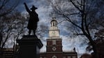 This photo shows Independence Hall in Philadelphia. The brick structure has a bell tower and steeple in the middle.