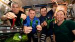 Astronauts pose with chile peppers grown aboard the International Space Station.