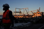 A worker walks past a fire-ravaged beachfront property in the aftermath of the Palisades Fire Monday, Jan. 13, 2025 in Malibu, Calif.