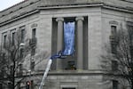 Workers on an aerial lift unfurl a new banner featuring President Donald Trump as it is installed on the façade of the US Department of Justice headquarters, Washington, DC, February 19.