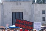 FILE - A person holds a “Protect Medicaid” sign in front of Oregon State Capital in Salem on May 1, 2025.