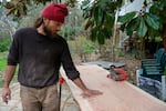 Alex Landt checks a redwood slab he's preparing to make a memorial bench for Taliesin Myrddin Namkai-Meche, April 19, 2023, in Ashland, Ore.