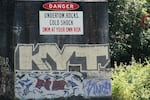 Signs warn of dangers of the Clackamas River near high rocks.
