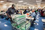 Election workers sort ballots at the Maricopa County Tabulation and Election Center in Phoenix. The workers wear colored lanyards symbolizing their party: red for registered Republicans, yellow for Independents and blue for Democrats. They work in pairs with partners chosen from different political outlooks.