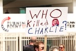 A person carries a sign that reads "Who killed Charlie" at a makeshift memorial for right-wing activist and Turning Point USA founder Charlie Kirk outside of their headquarters in Phoenix, Arizona. Social media has been fertile ground for speculation around what motivated the alleged killer, Tyler Robinson. It has also spread many conspiracy theories about the killing.