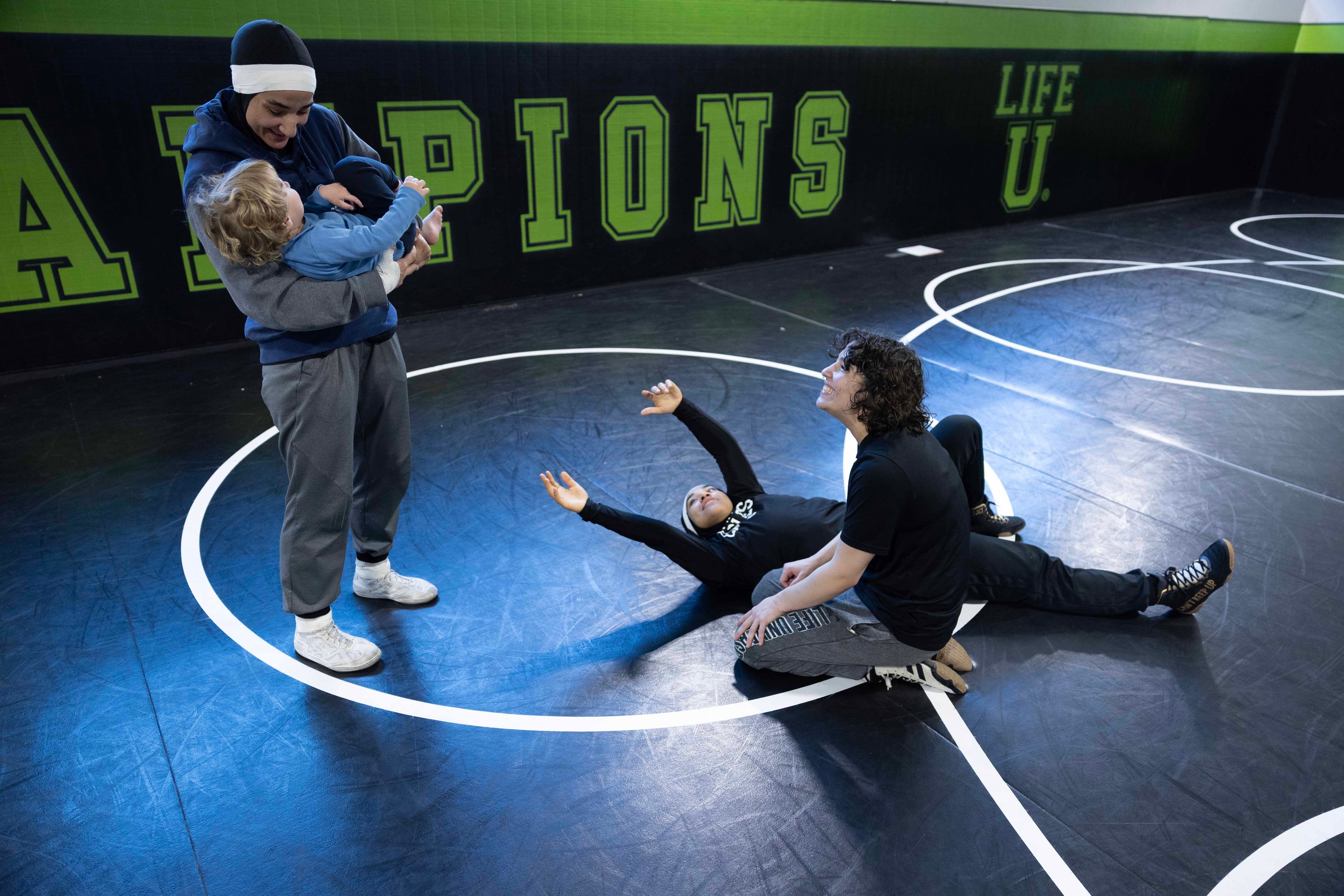 Jamilah McBryde holds her coach's son while teammate Megan Stottsberry and sister Latifah watch.
